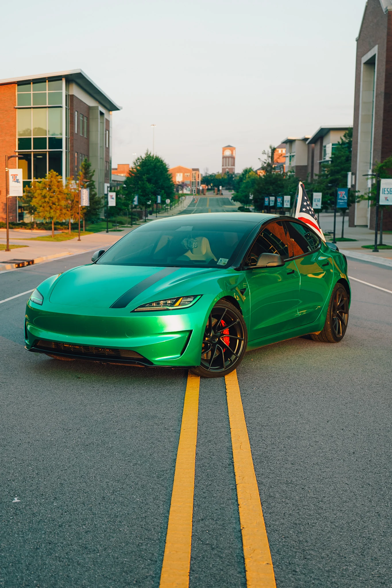 Green Tesla Model 3 photographed with an American flag