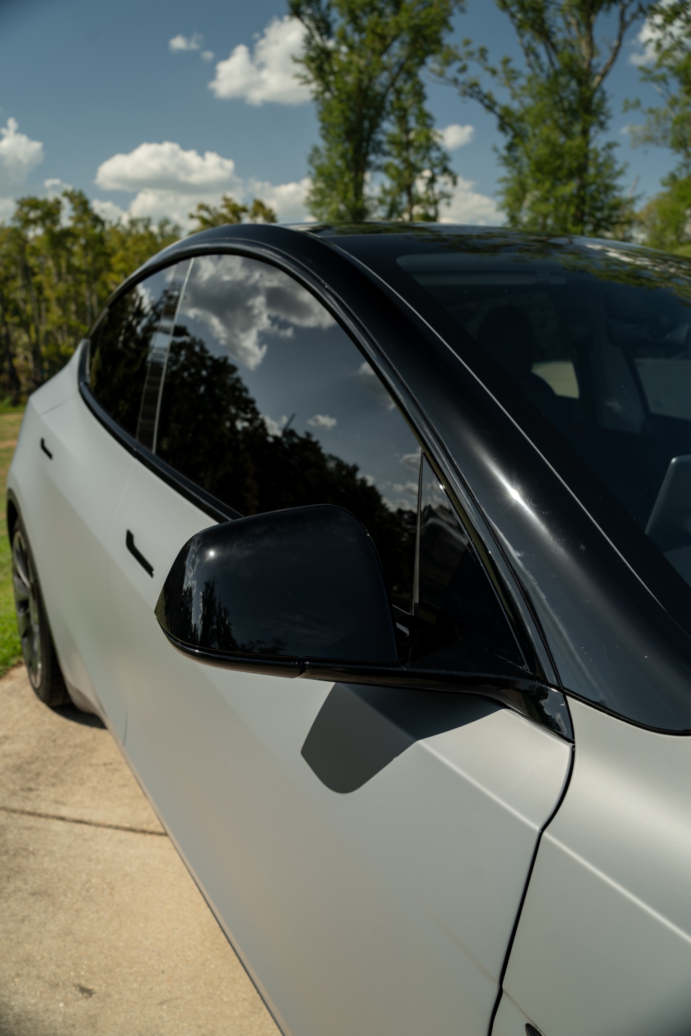 Close view of matte gray Tesla Model Y with black mirror and roof